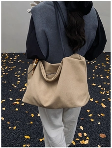Back view of a large khaki suede tote bag on a model featuring minimalist black straps