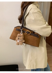 Dettaglio borsa sottobraccio in pelle scamosciata marrone con fibbia dorata e orsetto