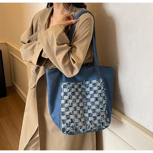 Détail du sac cabas en denim bleu avec patch jacquard à damier et bords effilochés