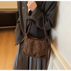 Detail of leopard print shoulder bag with brown leather trim styled with grey suit