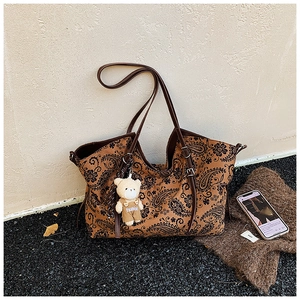 Close-up of vintage brown paisley tote bag with a cute bear charm and adjustable strap