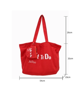 Detailed view of red canvas tote bag with white lettering and specific dimensions