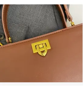 Gros plan d'un sac à main en cuir marron avec un fermoir rotatif rectangulaire doré poli
