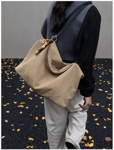 Detail view of khaki canvas tote with retro wooden bead charm in an autumn setting
