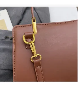 Gros plan sur la ferrure dorée et la texture du cuir d'un sac à main marron chic