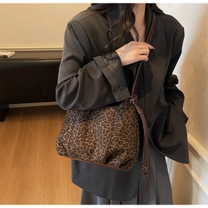 Chic leopard print tote bag with long brown straps shown in a stylish indoor lifestyle setting