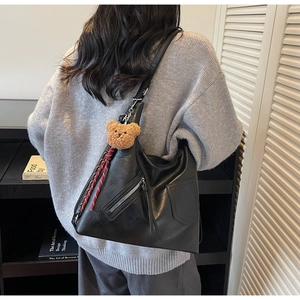 Detailed back view of a large black leather tote bag with silver zipper and bear charm