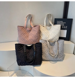 Detail of quilted tote bags featuring S-shaped patterns in pink, white, black, and grey
