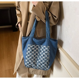 Détail du sac cabas en denim bleu avec une poche avant au design damier patchwork élégant