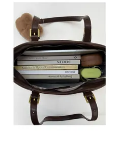 Vertical top view showing large interior capacity of brown leather tote bag with tablet and books