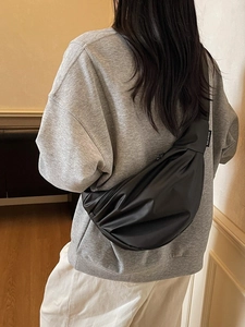 Black crescent pleated crossbody bag shown on a model for a trendy commute look