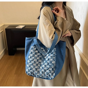 Détail du sac cabas en denim bleu avec bords effilochés et motif à damier élégant