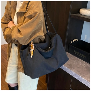 Detail of a large black canvas Hobo bag featuring a colorful beaded tassel charm