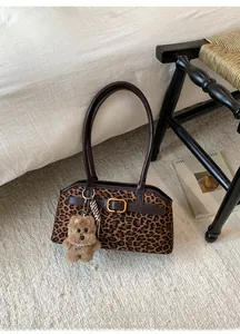 Dettaglio borsa baguette leopardata con fibbia dorata e ciondolo a forma di cane