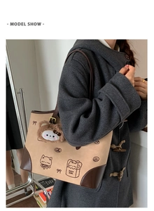 Detail view of a vintage beige tote bag with cute illustrations on a model's shoulder