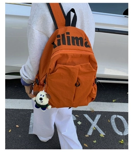 Detalle de mochila de nailon naranja resistente al agua con estampado ilima y colgante de perro
