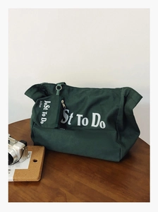Detail of dark green canvas tote bag with letter print and matching zipper pouch