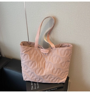 Detail of light pink quilted tote bag with S-pattern stitching and branded woven label