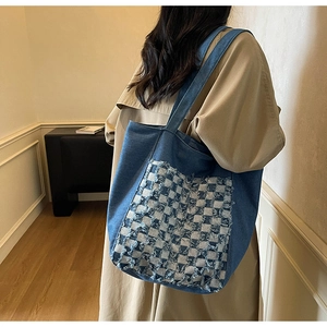 Gros plan du sac cabas en jean bleu avec une poche à carreaux et bords effilochés