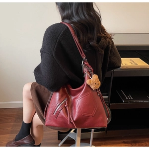 Close-up of a burgundy hobo tote bag featuring a leather texture and teddy bear charm