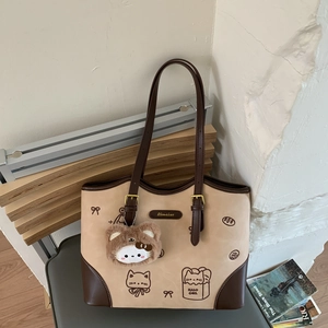 Close-up of contrast stitching tote with hand-drawn cat graphics and a plush charm