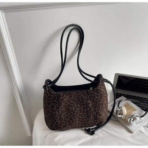 Detail of leopard print faux suede shoulder bag featuring drawstrings and zipper closure