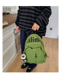 Detalle de mochila verde resistente al agua con letras alim y colgante de perrito