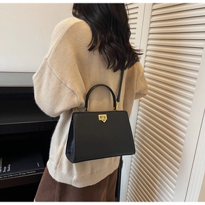 Structured black leather handbag with gold twist lock and adjustable shoulder strap