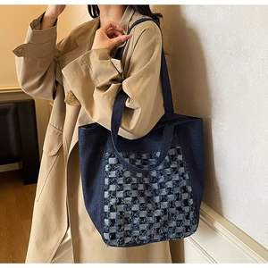 Détail du sac cabas en denim bleu avec une poche texturée à motif damier en 3D