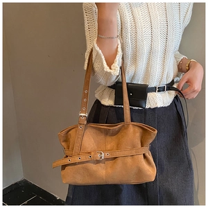 Detail view of brown suede tote bag featuring retro buckle and integrated shoulder strap