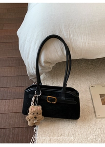Dettaglio della borsa retrò in pelle scamosciata nera con fibbia d'oro e ciondolo a cane