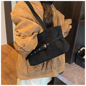 Macro detail of black suede tote bag with decorative metal buckle belt and retro strap