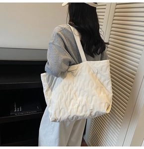 Side view of a white quilted tote bag with S-letter texture worn by a female model