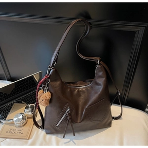 Detail of dark brown vintage faux leather tote with plush bear and laptop setup