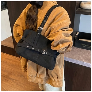 Detail of black faux suede tote bag with silver eyelet straps and adjustable buckles