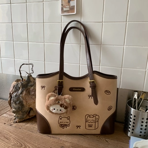 Detail of a large color-block tote bag with cute cat prints and a plush kitten charm