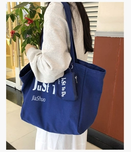 Detail view of navy blue canvas tote bag with removable zipper pouch and printed text