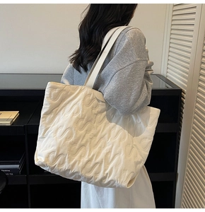 Detailed close-up of a white quilted tote bag with unique S-pattern embossed texture