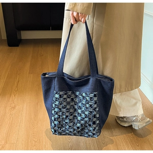 Gros plan d'un sac cabas en jean bleu avec des détails de franges et coutures à carreaux
