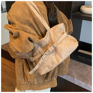 Détail d'un sac cabas en daim marron avec boucle métallique et plis texturés élégants