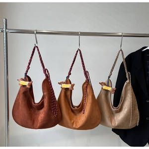 Three suede hobo bags in brown tones with woven rope straps and dachshund plush charms