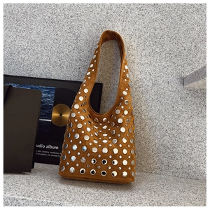 Sac hobo en daim marron avec rivets argentés sur fond minimaliste en pierre naturelle