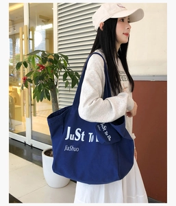 Detail of navy blue canvas tote bag with white lettering and matching small hanging pouch