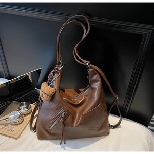 Detailed shot of coffee brown PU leather tote bag with a cute plush bear charm accessory