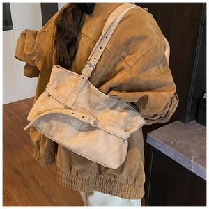 Close-up of large khaki suede tote bag with silver buckle details worn with corduroy jacket