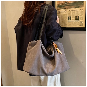 Macro shot of a grey large-capacity vintage tote bag with beaded tassel and suede texture