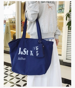 Detail of navy canvas tote bag with small matching zipper pouch and printed text lettering