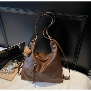 Close-up of vintage brown leather tote bag with soft PU texture and cute bear charm