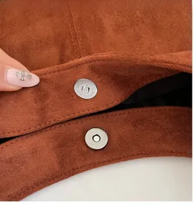 Detail of silver magnetic buckle on brown suede handbag with high quality metal hardware