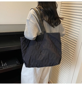 Detailed view of the large black quilted tote bag with S-pattern stitching on shoulder